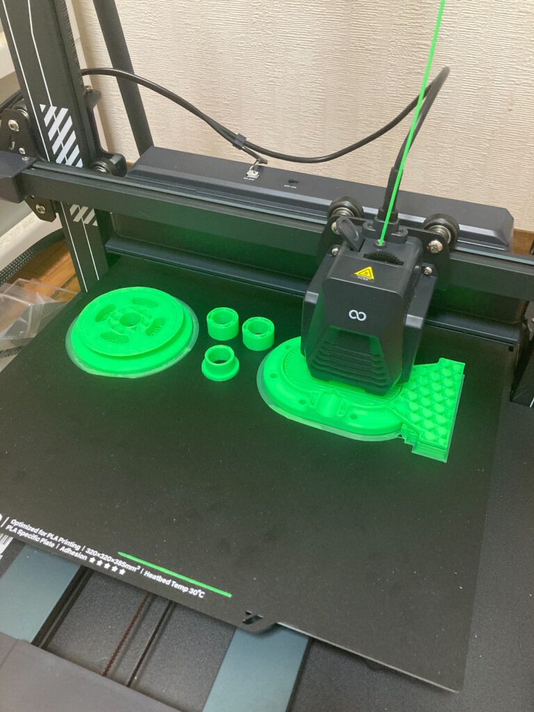 3Dプリンターが緑色の部品を印刷中の画像